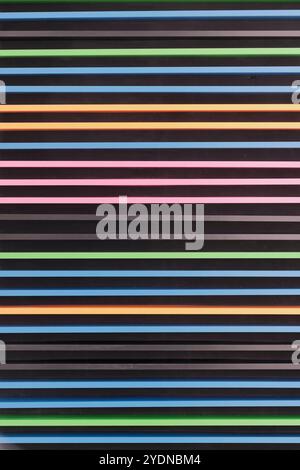 Textured wall featuring vibrant horizontal stripes against dark background. Evenly spaced lines form modern and visually striking pattern, adding bold Stock Photo
