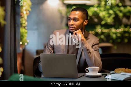 Afro manager drinking tea and using personal computer at cafe Stock Photo