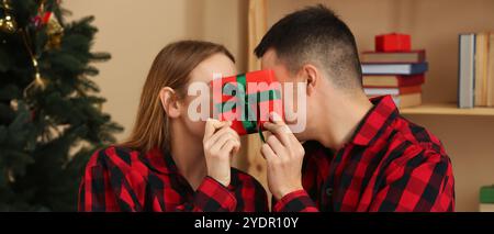 Young couple in pajamas and with gift at home on Christmas eve Stock Photo