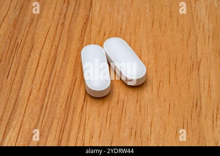 Macro image of generic acetaminophen (paracetamol) tablets, with no markings, on a wooden table. Stock Photo