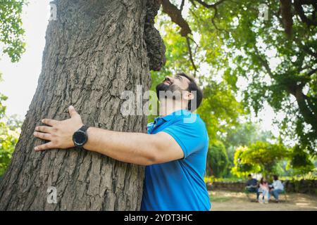 Man Protecting Tree young indian man embracing large tree, Save planet, ecology, climate ...