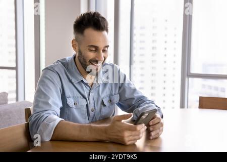 Cheerful handsome Hispanic man playing online game on smartphone Stock Photo