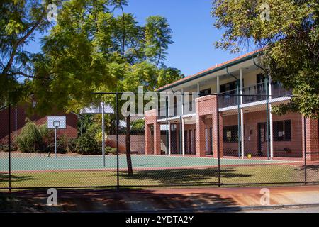 The image showcases an Australian school featuring a multi-level brick building with a spacious balcony overlooking a well-maintained basketball court Stock Photo