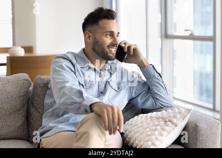 Dreamy happy handsome Hispanic freelancer man talking on cellphone Stock Photo