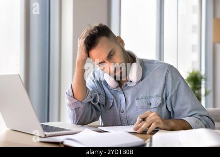 Tired focused adult Latin student man getting difficult task Stock Photo