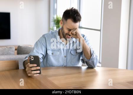 Cheerful young Latin man using mobile phone and laughing Stock Photo