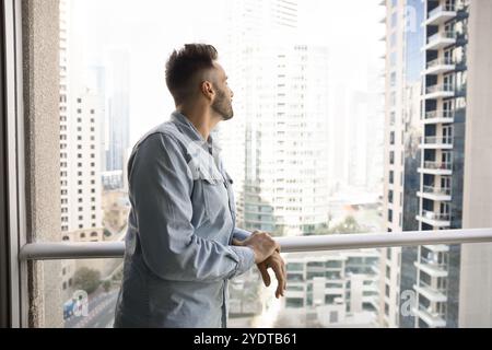 Thoughtful successful Caucasian homeowner man looking at downtown city view Stock Photo