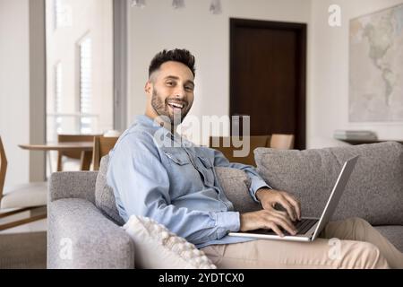 Cheerful handsome freelance entrepreneur man using laptop at home Stock Photo