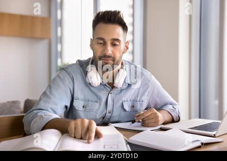 Focused adult Latin student man reading learning textbook at home Stock Photo