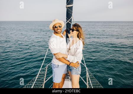 Happy couple embracing on a sailboat, enjoying a romantic and carefree day on the ocean. Stock Photo