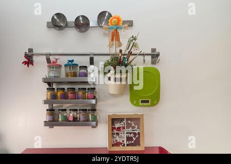 Spice rack wall in a modern kitchen with many colorful containers, an electronic scale, a pot with plants, and an array of other kitchen furnishings Stock Photo