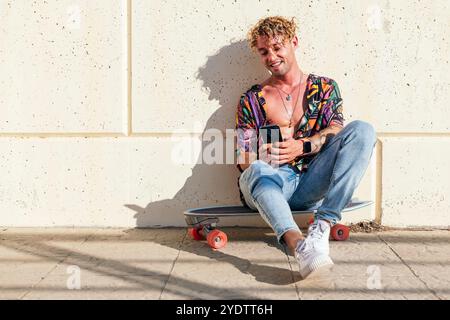 hipster sitting on skateboard and using phone Stock Photo