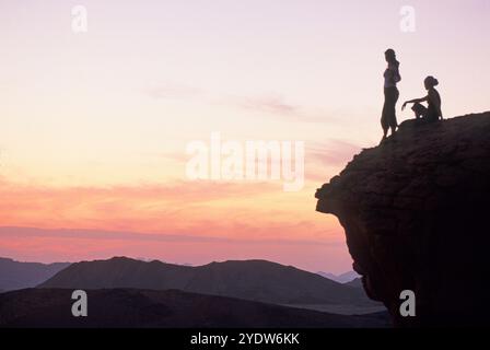 Two women sitting on a rock enjoying sunset in the desert of Wadi Rum, Jordan, Middle East Stock Photo
