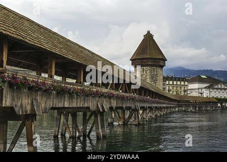 The Kapellbrucke (Chapel Bridge) is a covered wooden footbridge spanning diagonally across the Reuss River in the city of Lucerne, Switzerland, Europe Stock Photo