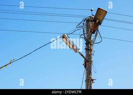 A tall telephone pole standing upright with a bright street light securely attached to it, offering illumination to the surrounding area Stock Photo