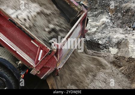 A dump truck unloads a load of sand on a construction site Stock Photo