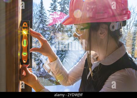 Close up on construction inspector woman using torpedo spirit level to measuring an interior vertical surface next to a window. air quality inspection Stock Photo