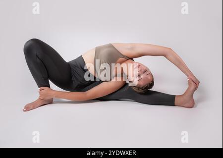 Woman sitting on the floor doing Revolved Head to Knee yoga Pose (Parivrtta Janu Sirsasana) Stock Photo
