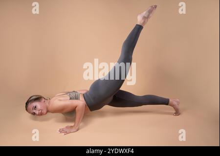 Smiling woman doing a Chaturanga (dandasana) pose with a raised leg Stock Photo