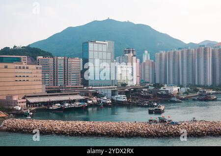 Hong Kong, China - April 27, 2009: High-rise residential buildings near the waterfront with a tugboat in the foreground. Stock Photo