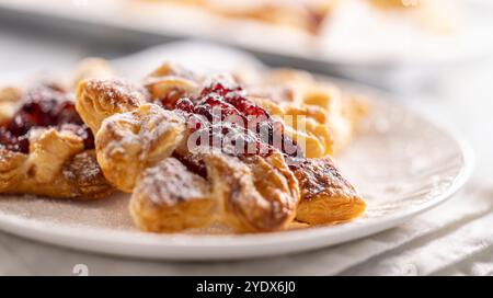 Sweet dessert pastries made of puff pastry with strawberry jam filled with caramelized apple sprinkled with powdered sugar. Stock Photo