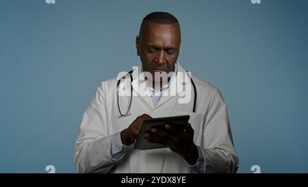 Focused serious African American man doctor physician write medical treatment plan for patient using digital tablet ethnic male professional Stock Photo