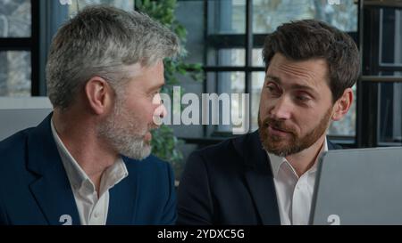 Close-up two joyful Caucasian men businessmen looking at computer screen discussing financial trading project at office meeting discuss presentation Stock Photo