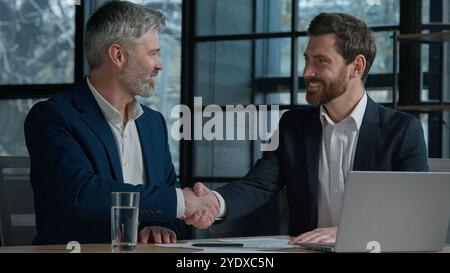Close-up unrecognizable Caucasian men businessmen business partners employees sign contract document paperwork shaking hands successful partnership Stock Photo