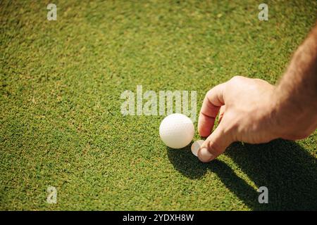 A man placing a golf ball and moving the marker on the green, focusing on setting up the perfect shot at the golf course. Stock Photo