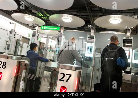 Travelers lining up at the UK border control inside a LHR heathrow airport terminal 5 with unique circular ceiling lights Stock Photo