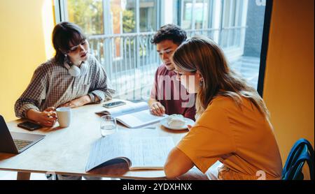 A group of high school students focuses intently on their work, collaborating and studying together in a bright, modern setting, emphasizing teamwork Stock Photo