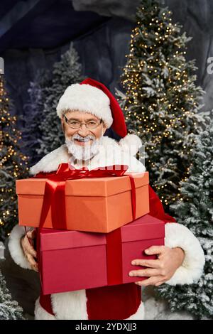 A cheerful Santa Claus holds vibrant gift boxes surrounded by festive trees in winter joy. Stock Photo