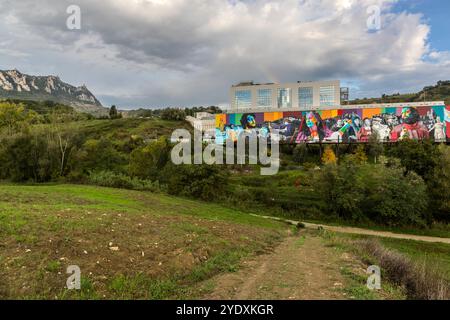 The roughly 1,300-square-metre mural "The History of San Marino" by Brazilian artist Eduardo Kobra (2022) covers the facade of a packaging factory in Faetano. In the background rise the three towers of San Marino's historic centre, and a rainbow above the building lends the scene a magical moment. Strada del Sabattino, Faetano, San Marino. Stock Photo