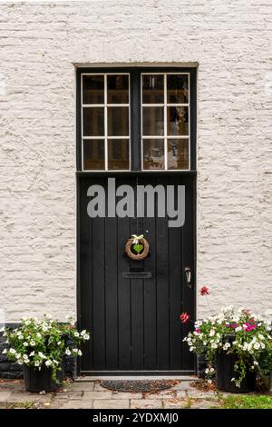Picturesque black door with a heart shaped ornaments and flower pots, medieval Flemish architecture in Bruges, Belgium Stock Photo