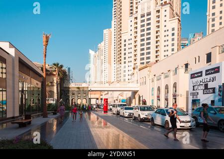 Dubai, UAE - October 17, 2016: People walking along a busy street with modern skyscrapers in the background. Stock Photo