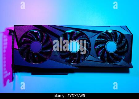 Close-up of high-performance graphics card with three cooling fans with neon lighting. Modern video card for gaming and advanced computing Stock Photo