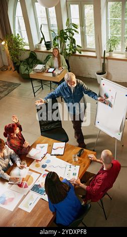Business leader provides mentorship during meeting, helping team members develop actionable plans for success. Top-down view. Stock Photo