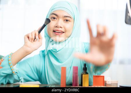 A young female beauty blogger is recording a vlog video on a smartphone using the ring light. Shot through the ring Stock Photo