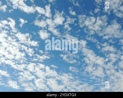 bright bright blue sky with many separate feathery clouds, airy background with wind movement in clouds, calmness and ease of flight in natural sky Stock Photo