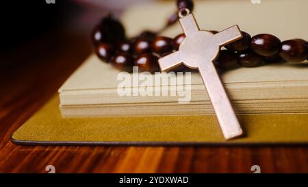 Dark red copper cross leaning against an old open book symbolizing the spread of Jesus Christs love among Christians reflecting faith devotion and the Stock Photo