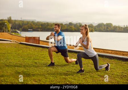 Active sporty young couple man and woman doing stretching exercising in nature. Stock Photo