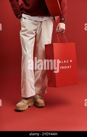 A stylish young man with curly hair joyfully holds shopping bags in a bright studio environment. Stock Photo