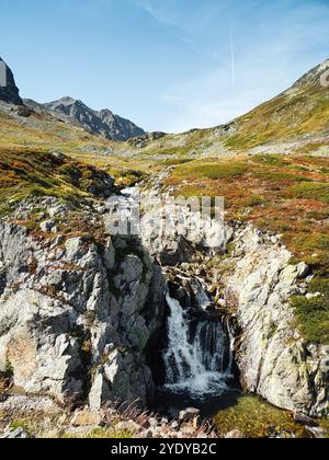 Mountain stream in alpine valley. Waterfall near Flüela mountain Pass road between Silvretta and Albula mountain ranges. Stock Photo