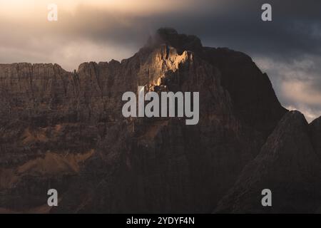 Foreboding light breaks through storm clouds, casting dramatic shadows over the rugged mountain peaks of Cadini di Misurina in the Italian Dolomites. Stock Photo