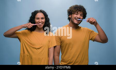 Multiracial couple Hispanic woman girl and Indian man Arabian guy holding tooth brush pretend brushing teeth dental care using toothbrushes oral Stock Photo