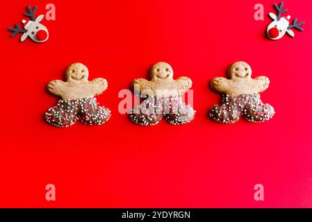 Three gingerbread men and 2 little reindeer on a red background. Copy space Stock Photo