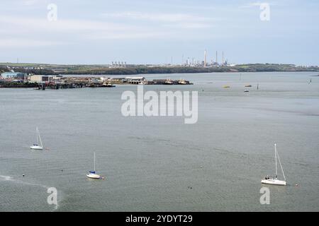 Sailing yachts are moored in Milford Haven beside the Pembroke Dockyard, with Pembroke Power Station and Pembroke Oil Refinery behind. Stock Photo