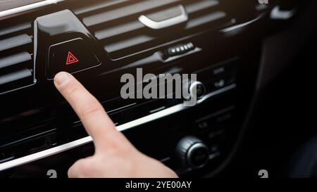 Man pressing red triangle car hazard light button Stock Photo