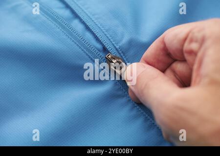 Close-up shot of a zipper on a blue jacket. Unzip a zip. Close up. Stock Photo