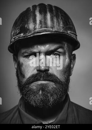 Man builder. Closeup portrait of serious male builder in hard hat. Construction worker, engineer or architect in protective helmet. Bearded mechanical Stock Photo